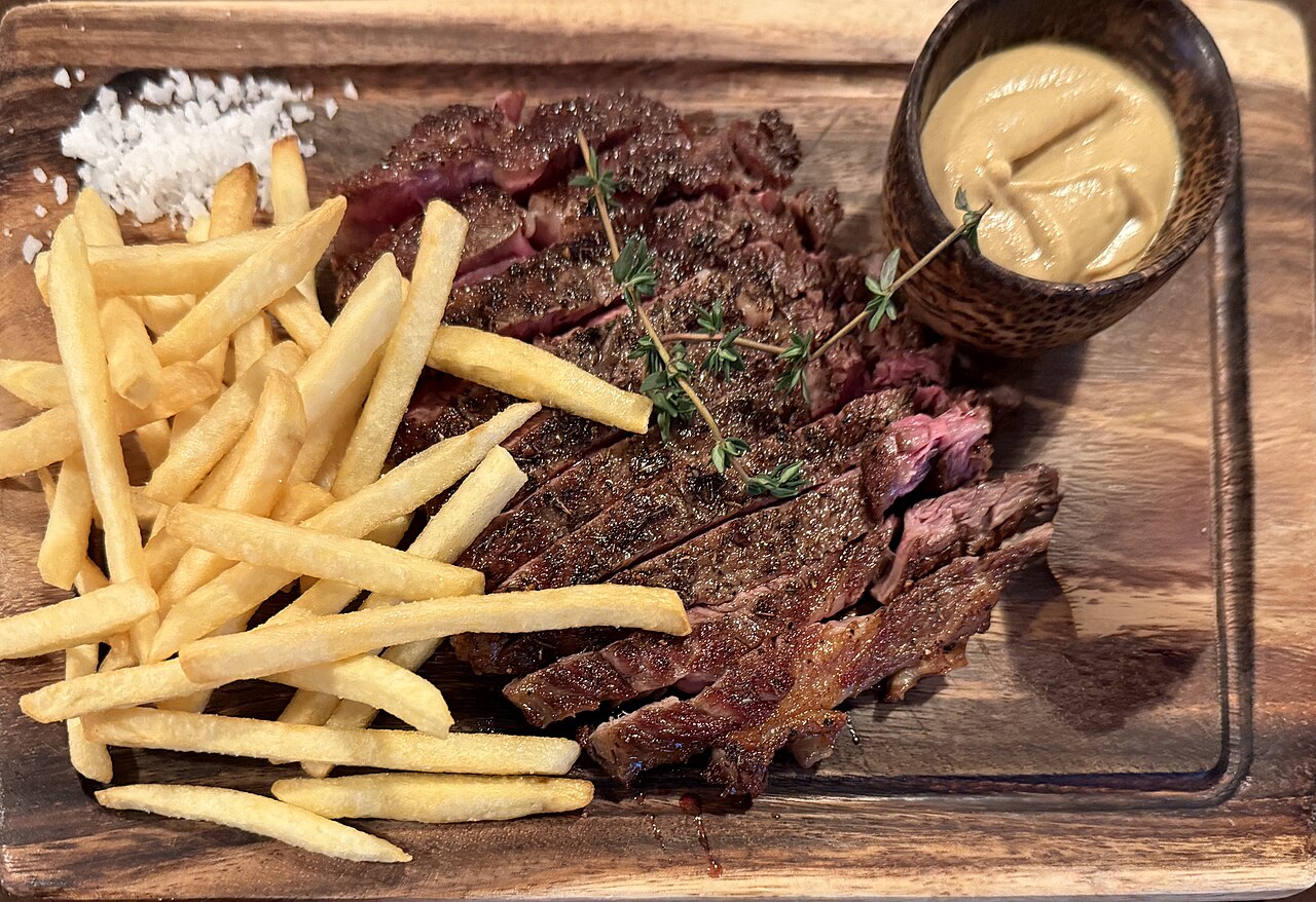 Sliced steak frites with fries on a wooden board